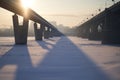 The sun shines across the city bridge over the frozen river on a sunny day. Royalty Free Stock Photo