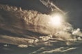 The sun shines through the clouds against the background of a gray sky with a rare cloudiness. Heavenly cloudscape. Royalty Free Stock Photo