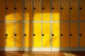 Sun shines on empty elementary school hall, numbered lockers at the wall