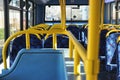 Sun shines on empty interior of London double decker bus, yellow holding rails and blue seats
