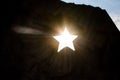 The sun shines through a hole in the shape of a Soviet star in an old monument