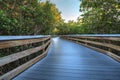 Sun shines through mangrove trees that line a Boardwalk leading down to the beach of Clam Pass