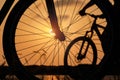 The sun shines through the wheel of a bicycle with blurred silhouette of bicycle rider