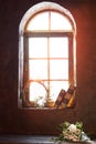 Sun is shining in a beautiful window on which there are old books and lay a bouquet of flowers of roses. Bright evening sunlight Royalty Free Stock Photo