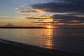 Sun shining from behind clouds with island silhouette