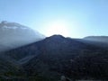 The sun is shining from behind the mountain. View from below. Beautiful natural landscape