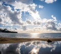 Sun shining through clouds and reflecting in the low tide sea water. Royalty Free Stock Photo