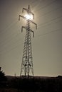 Sun shining through high voltage power lines on power pylons Royalty Free Stock Photo