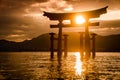 Sun shining through the Miyajima torii gate with mountains in the background during a stunning sunset. The large Japanese torii Royalty Free Stock Photo