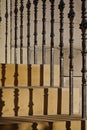 Sun shining through ornate black stair banister posts onto a golden sandstone staircase