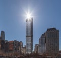 The sun is shining over a skyscraper and reflecting the light on the nearby building