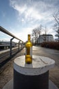 Sun shining through a Wine Bottle, standing on a Bollard, on a Dock, on a mild Winter Morning