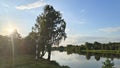 The sun is sinking to the horizon and its rays shine over the crowns of trees on the riverbank. Colorful cloudy sky at sunset in s Royalty Free Stock Photo