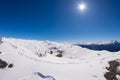 Sun star glowing over snowcapped mountain range and high mountain peaks in the italian alpine arc, in a bright sunny day of winter Royalty Free Stock Photo