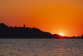 The sun at sunset behind the lighthouse and cape Higer, Euskadi Royalty Free Stock Photo