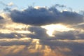 The sun at sunset or dawn behind the clouds, shines through. The sun`s rays in the sky Royalty Free Stock Photo