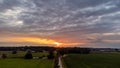 Sun Sunshine In Sunset Bright Sky. Beautiful Evening Sky Above Rural Landscape With Country Road. Young Green Wheat Royalty Free Stock Photo