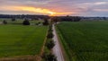 Sun Sunshine In Sunset Bright Sky. Beautiful Evening Sky Above Rural Landscape With Country Road. Young Green Wheat Royalty Free Stock Photo