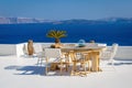 A sun terrace with a wooden table and chairs in Thira, Santorini island, Greece. Beautiful rest place over the caldera Royalty Free Stock Photo