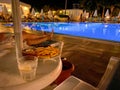 Sun umbrellas, sun loungers and a pool of warm clear water at the all-inclusive hotel at night in a warm tropical oriental