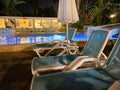Sun umbrellas, sun loungers and a pool of warm clear water at the all-inclusive hotel at night in a warm tropical oriental