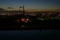 The sun went down outside the city. Above the city, electric high poles and pipes from the city's heating systems Royalty Free Stock Photo