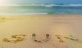 Sun written with various shells on the sand with ocean background Royalty Free Stock Photo