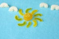 Sun from yellow marmalade with rays and white marmalade clouds on a blue felt background. Sugar sweet Christmas sweets. Different