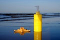 Sunbath lotion sun protection in yellow plastic bottle and sea star on water background, copy space Royalty Free Stock Photo