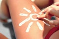 Sunbath protection. Woman using Suntan Lotion At The Beach In Form Of The Sun on leg. Royalty Free Stock Photo