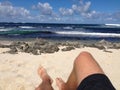 Sunbathing with legs stretching across beach towards the sea Royalty Free Stock Photo