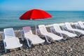 Sunbathing plastic beds and red umbrella on the beach Royalty Free Stock Photo