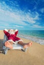 Sunbathing Santa Claus relaxing in bedstone on tropical beach Royalty Free Stock Photo