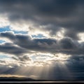 Sunbeams break through dense dramatic clouds over a distant mountain range Royalty Free Stock Photo