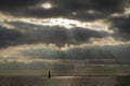 Sunbeams breaking through cloud cover, a sailboat sailing on a lake near Amsterdam.