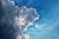 Sunbeams through a dark thundercloud in a blue sky