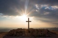 sunbeams illuminating a cross on hilltop