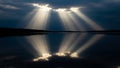 Sunbeams Breaking Through Dark Clouds Reflecting on Calm Water light rays god rays Royalty Free Stock Photo