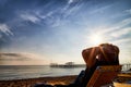 Sunbed on the sand beach, man on it and view to water of sea, pierce and blue sky with white clouds in a nice day, morning or Royalty Free Stock Photo