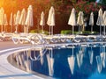 Sunbeds and folded umbrellas next to swimming pool Royalty Free Stock Photo