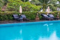 Sunbeds and parasols on wooden deck nearby swimming pool Royalty Free Stock Photo