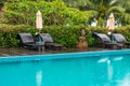 Sunbeds and parasols on wooden deck nearby swimming pool Royalty Free Stock Photo