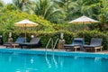 Sunbeds and parasols on wooden deck nearby swimming pool Royalty Free Stock Photo