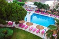 Sunbeds and parasols on wooden deck nearby swimming pool Royalty Free Stock Photo