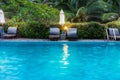 Sunbeds and parasols on wooden deck nearby swimming pool Royalty Free Stock Photo