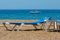 Sunbeds on rocky beach and parasailing speed boat waiting for customers