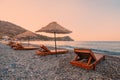 Sunbeds and sun umbrellas await vacationers on the shingle beach at Ovabuku beach on the Datca Peninsula in Turkey. Royalty Free Stock Photo