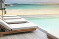 Sunbeds on Swimming Pool Wooden Deck with White Sand Beach and Blue Sea Background Royalty Free Stock Photo