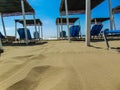 Sunbeds under straw sunshades on the empty sandy beach. Royalty Free Stock Photo