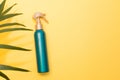 Sunblock spray green bottle on yellow background with palm leaf with a copy space